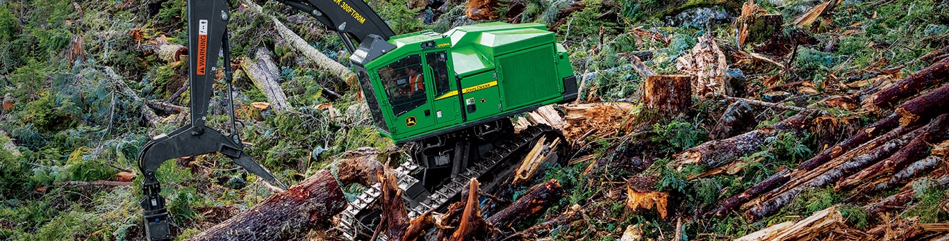 John Deere 959ML shovel logger gathering and moving felled trees from the side of mountain