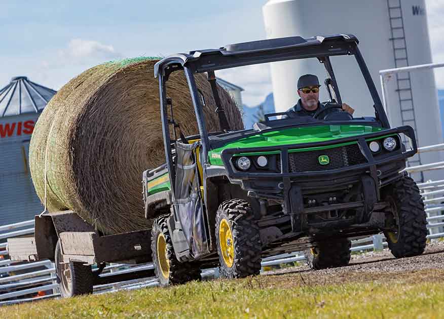 John Deere Gator Utility Vehicle towing a hay barrel on a tailer