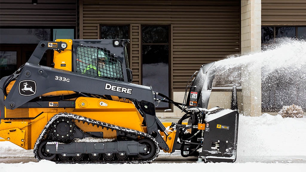 Person clearing snow with a Utility Tractor equipped with a snow blower and loader.