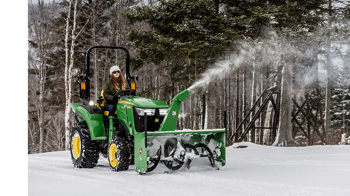  Person clearing snow in laneway using a compact utility tractor equipped with a snowblower.