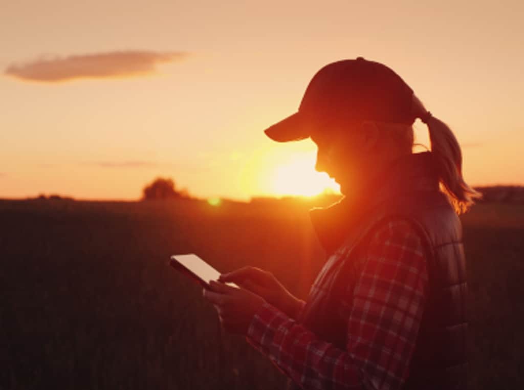a woman outside at sunset looking at a tablet