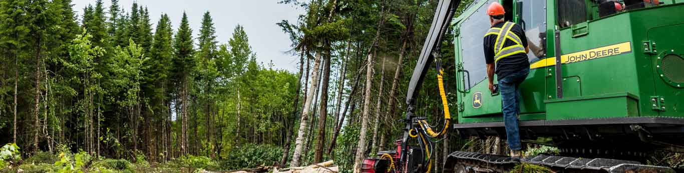 Man standing on John Deere Forestry equipment in a logging worksite