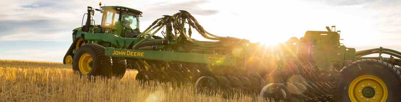 John Deere Tractor with attachment in the field during sunrise