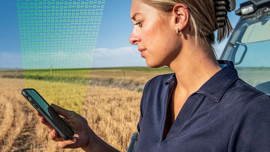 a woman holding cell phone in field with data streaming into it