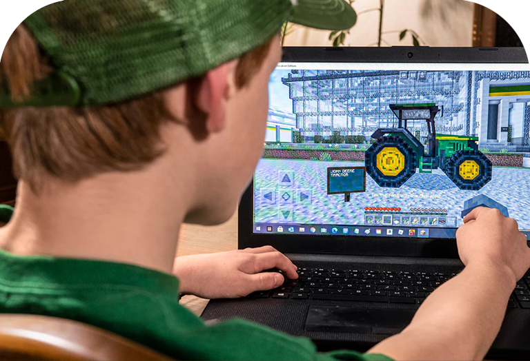 A boy works on a John Deere tractor creation in the Minecraft game