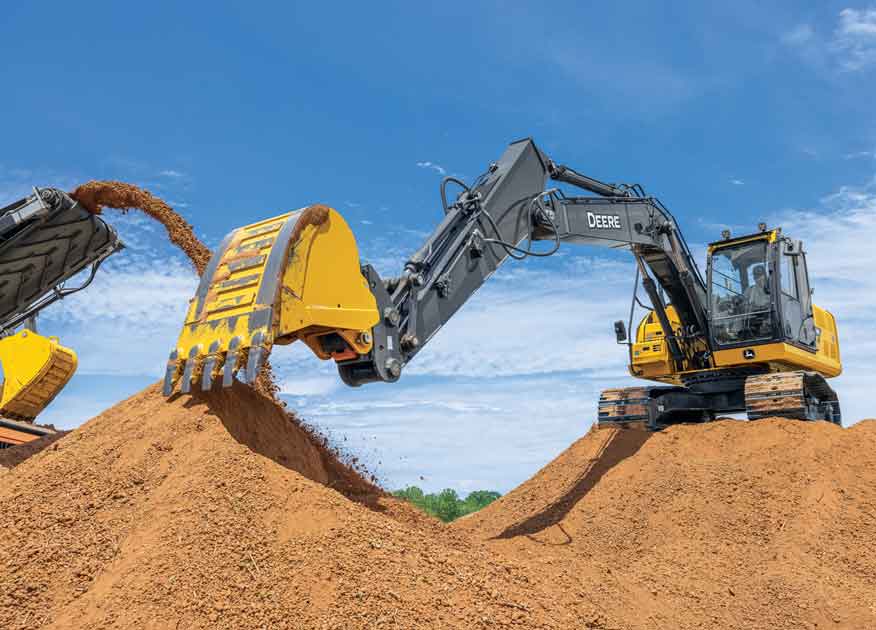 John Deere construction equipment being operated in a dirt field with dirt falling out of the bucket