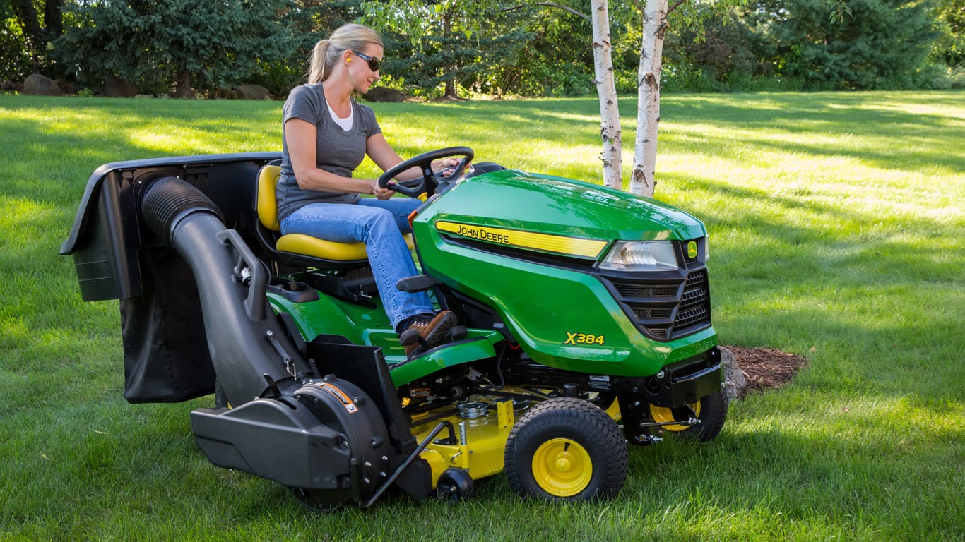 image of woman on lawn tractor with collection system attached